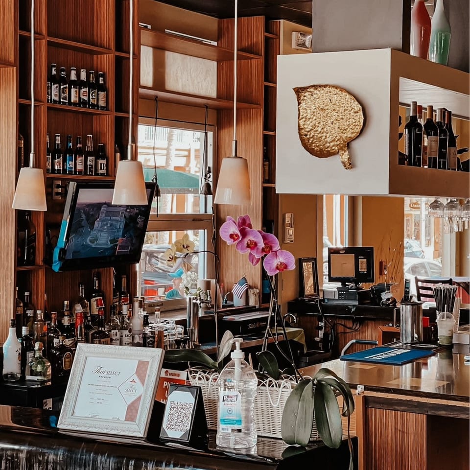 A well-stocked bar at Thai Thani Celebration with liquor bottles, orchids, and a "Thai Select" award.