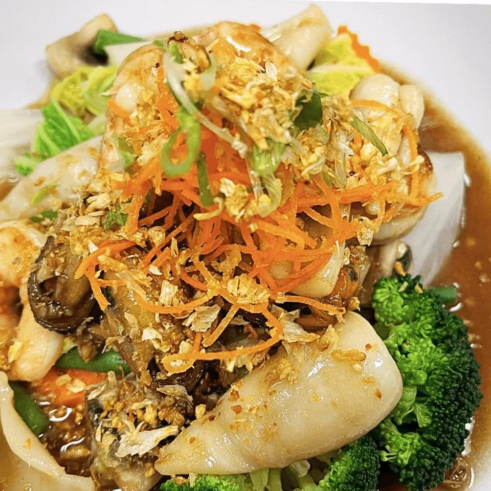 Thai dish with shrimp, broccoli, carrots, mushrooms, and fried garlic in a savory sauce.