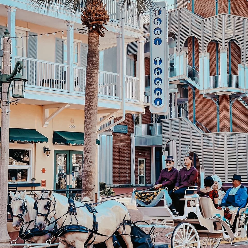Horse-drawn carriage with people in front of Thai Thani restaurant and other buildings.